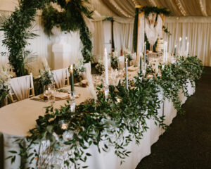 rustic wedding table decoration with flowers, leaves and green and white taper candles