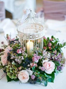 birdcage with flowers and burning candle 