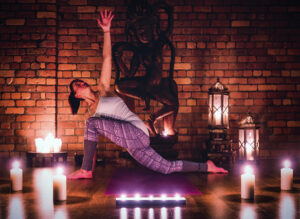 woman practicing yoga with different sizes of candles